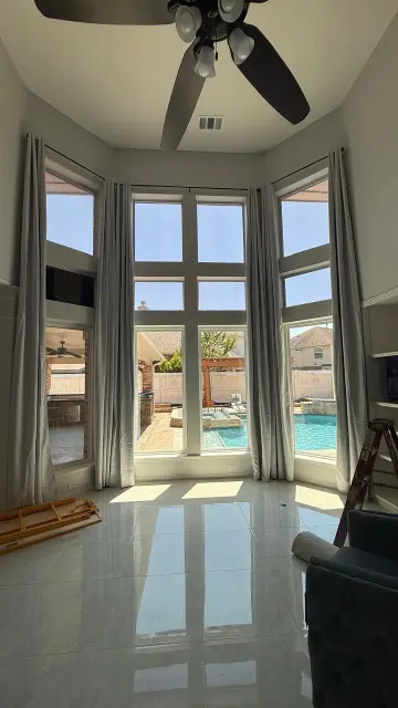 Bay window overlooking backyard pool in bright living room remodel – Engineered hardwood floors and open design Houston TX